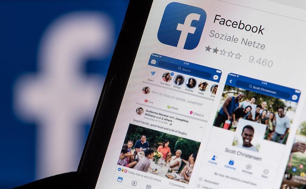 Человек держит в руках смартфон, пролистывая Facebook. Иллюстративное фото взято с fikiwiki.com.