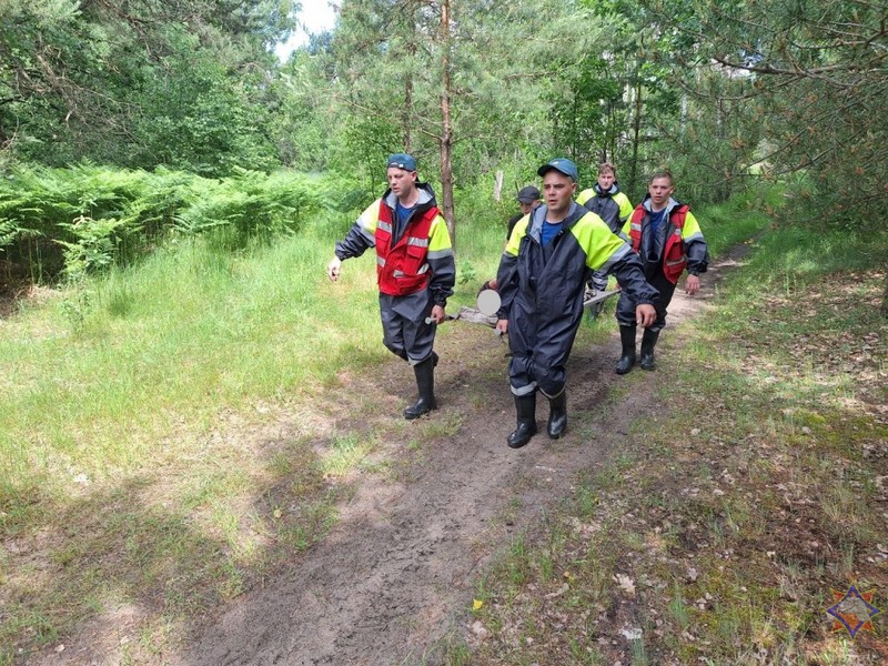 Мужчину несут на носилках спасенную пенсионерку. Фото: Брестское областное управление МЧС