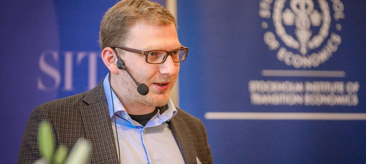 Лев Львовский, экономист и преподаватель BISEB, выступает на мероприятии с гарнитурой.